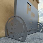 Expositor metálico personalizado para cabina de DJ en discoteca. Estructura de diseño fabricada a medida mediante corte láser en tono gris, con logotipos y el nombre "DJ David Ceballos" troquelados en los paneles laterales en forma de auriculares, para eventos en Málaga.