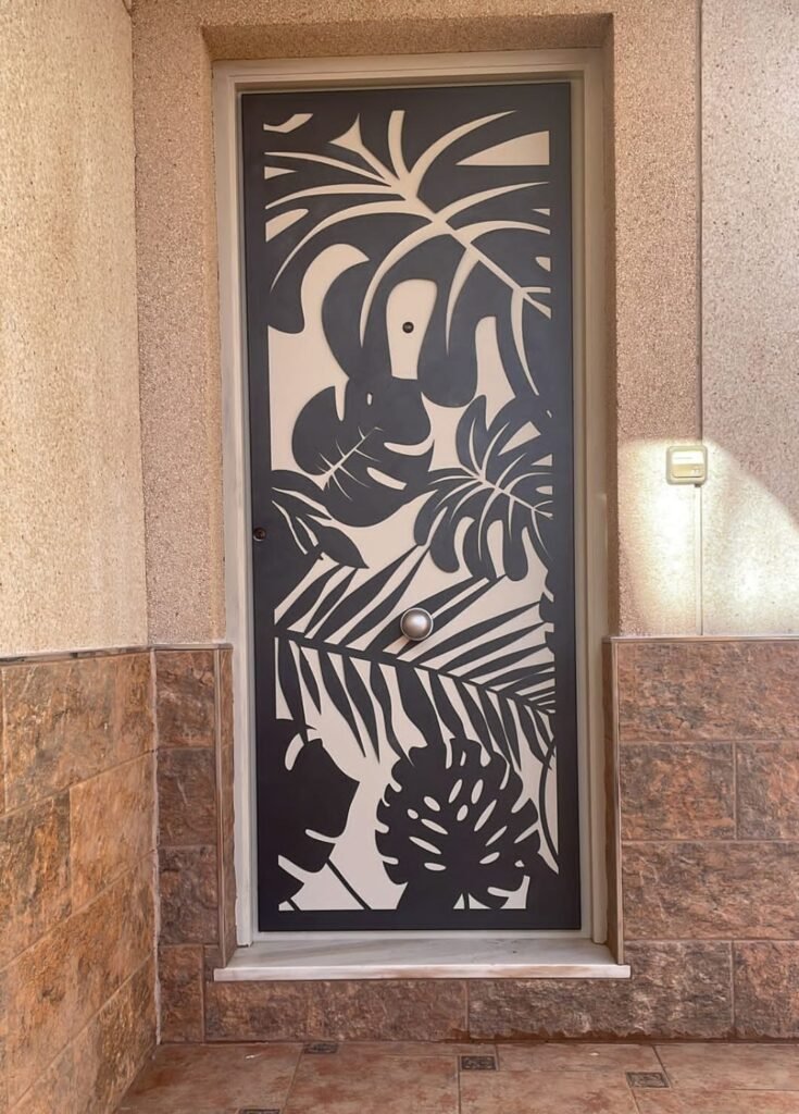 Puerta de entrada y cerramiento exterior en Cádiz. Diseño único en chapa con patrón botánico tropical fabricado a medida mediante corte láser