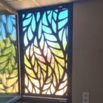 Rejas abatibles y de apertura para ventanas en metal oscuro, con un diseño orgánico de ramas entrelazadas en corte láser. Instalación de seguridad vista desde el interior hacia el jardín, aportando protección y paso de luz a un chalet independiente en Madrid.