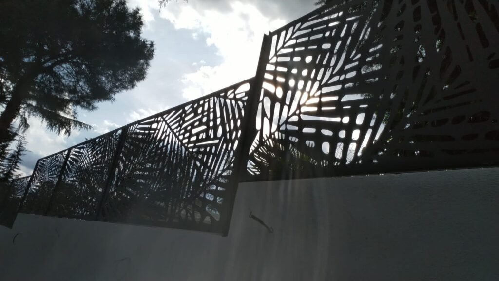 Instalación de valla metalica sobre muro de diseño de hojas de palmera, en acero inoxidable lacado al horno en color gris antracita en Madrid