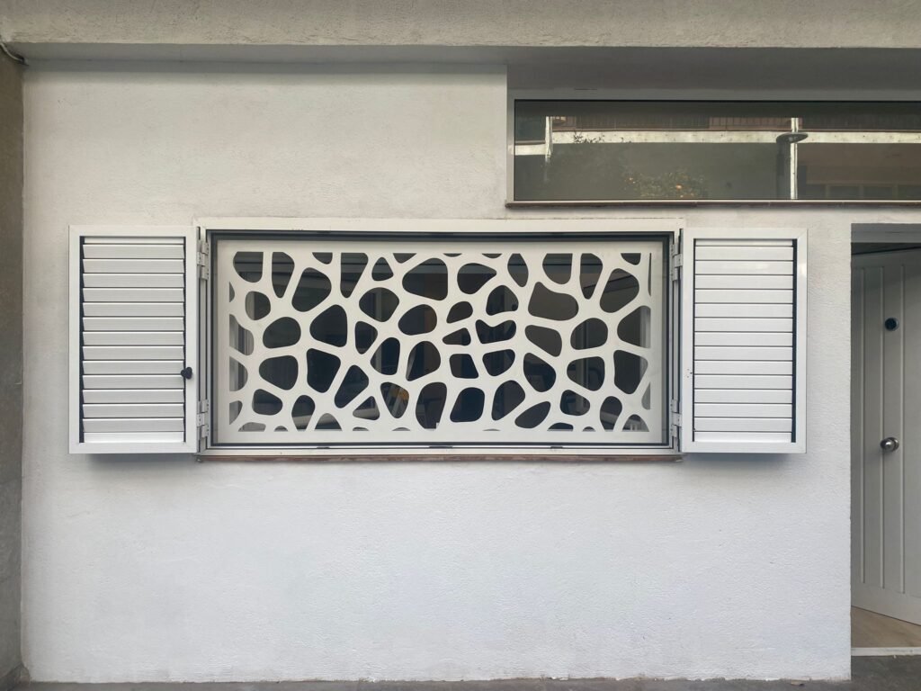 Rejas de hierro para ventanas diseñadas a juego con la puerta principal de la vivienda, en corte laser color blanco, diseño de circulos