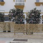 Valla exterior metálica en color dorado con diseño botánico de hojas en corte láser, instalada sobre un murete de piedra para delimitar la fachada ajardinada de un restaurante de lujo en Marbella.