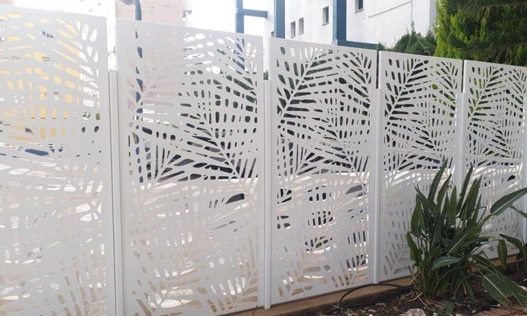Valla metálica para terraza de hotel en la costa de Valencia. Celosía exterior lacada en blanco con diseño botánico tropical fabricada en chapa de corte láser para separación de espacios