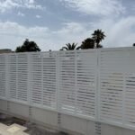 Valla perimetral metálica en color blanco diseñada para aportar privacidad, con un diseño personalizado de líneas horizontales en corte láser, instalada sobre un murete exterior en Almería.