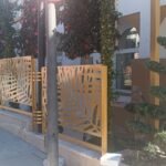 Valla perimetral metálica en acabado dorado con diseño botánico de grandes hojas en corte láser, instalada sobre un murete exterior para delimitar la terraza de un restaurante de lujo en Marbella.