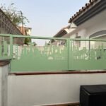Valla perimetral metálica en color verde claro con un diseño exclusivo de skyline de monumentos del mundo en corte láser, instalada sobre un muro exterior en una vivienda de Coín, Málaga.