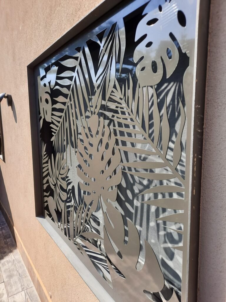 Reja de seguridad y celosía metálica en Barcelona. Personalización con diseño de hojas y patrón botánico tropical fabricado a medida mediante corte láser para ventana