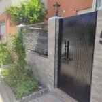 Puerta de entrada y valla metálica sobre muro en Madrid. Cerramiento exterior de diseño árabe en color negro fabricado en chapa mediante corte láser