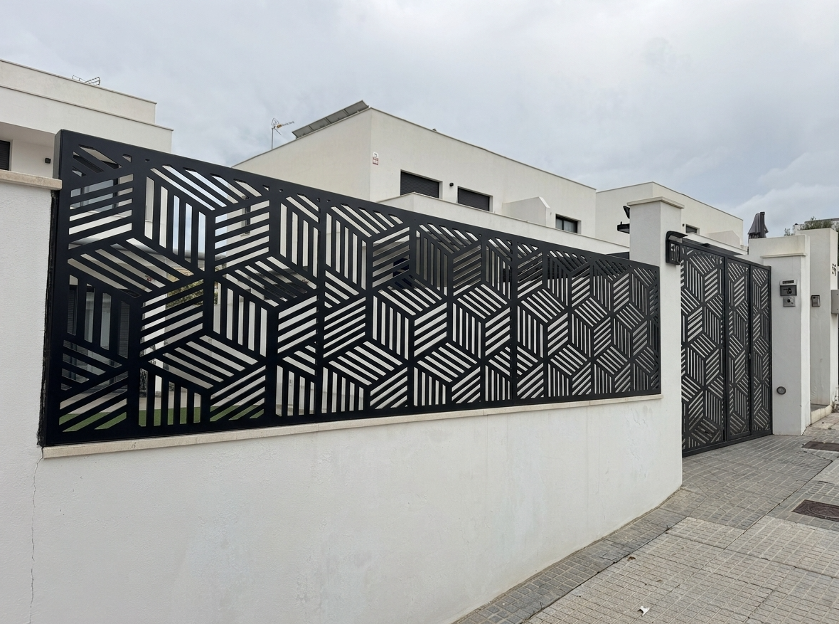 Valla metálica sobre muro en Alhaurín de la Torre, Málaga. Celosía metálica exterior lacada en negro con diseño geométrico de cubos 3D fabricada en chapa mediante corte láser