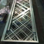 Celosía de acero mecanizada a medida con marco perimetral plegado y patrón geométrico para separación de ambientes en escaleras interiores.