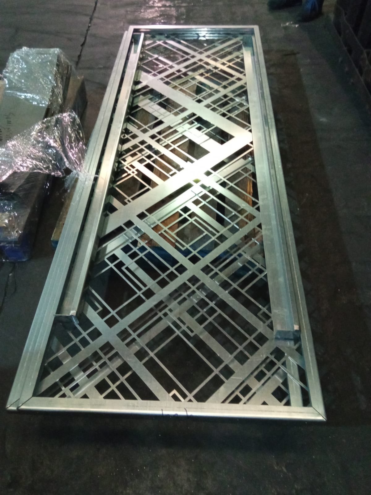 Celosía de acero mecanizada a medida con marco perimetral plegado y patrón geométrico para separación de ambientes en escaleras interiores.