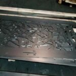 Panel de acero corten en corte láser con patrón de líneas entrelazadas para valla perimetral y puerta de diseño en Madrid.