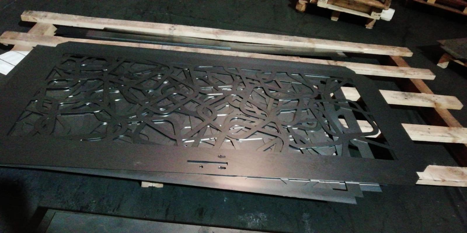 Panel de acero corten en corte láser con patrón de líneas entrelazadas para valla perimetral y puerta de diseño en Madrid.