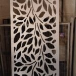 Panel vertical metálico tipo celosía fabricado mediante corte láser con un diseño de hojas entrelazadas, utilizado como separador divisorio para terrazas.